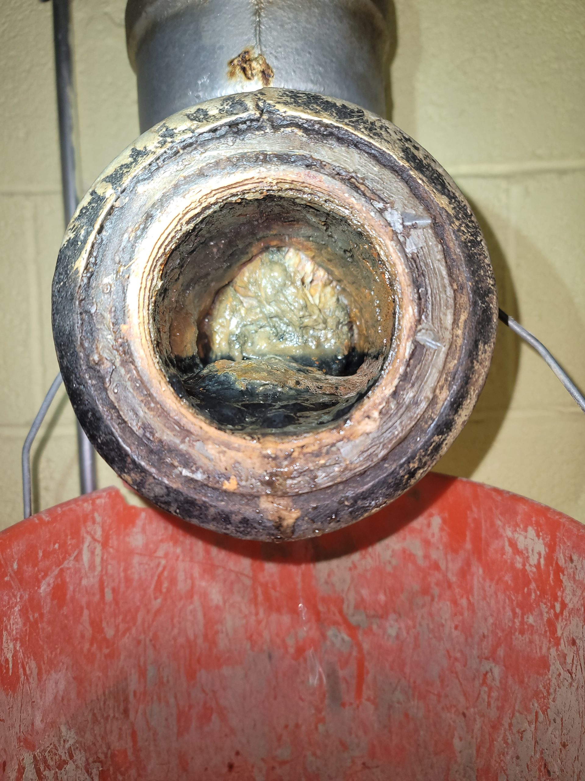 Inside view of an old cast iron sewer pipe in a Greater Cleveland home showing severe scale, buildup, and partial blockage requiring replacement
